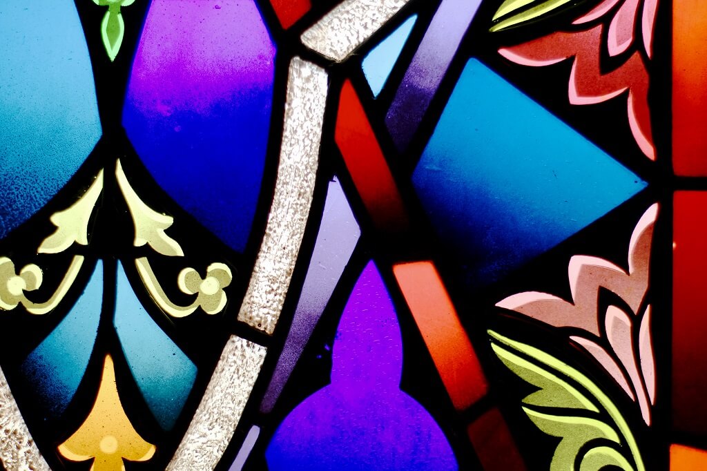 The photo shows a proud and beautiful purple, gold, red and green design of stained glass to help reflect on what you believe.