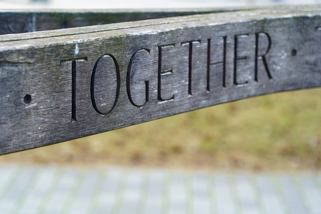 The photo is of a wooden plank with the word TOGETHER beautifully chiseled into it symbolizing bringing each side closer together. 